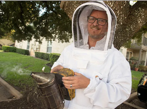 Keith, professional beekeeper, in a bee suit holding a smoker